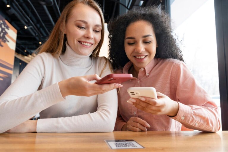 Two women looking at a phone screen with a QR code on the table, representing a conversion.