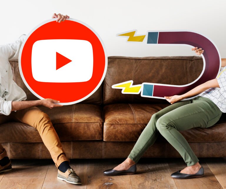 Two people holding a YouTube logo and a magnet to attract viewers with SEO.